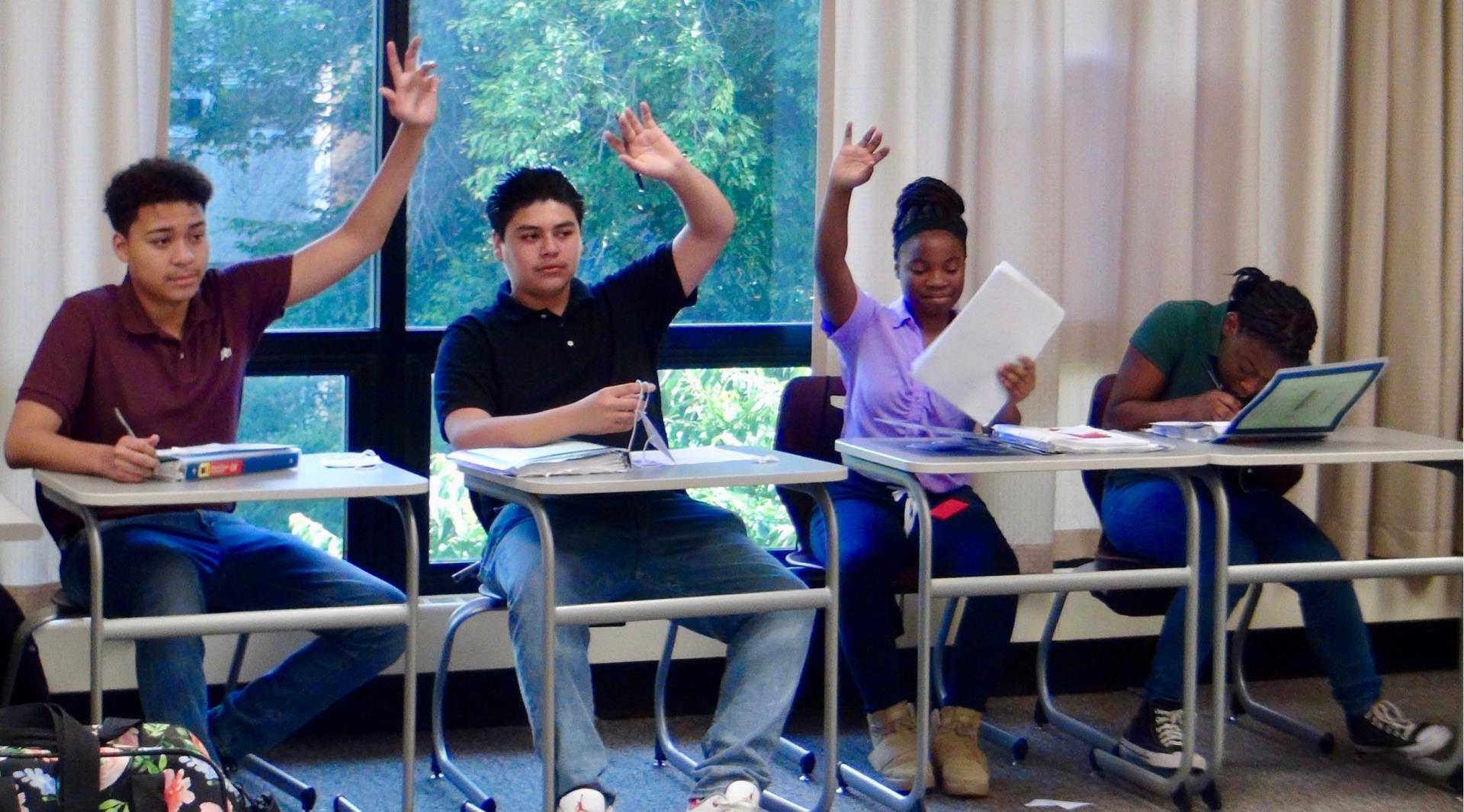 Teens raising their hands in a classroom