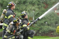 Firefighters with hose spraying water